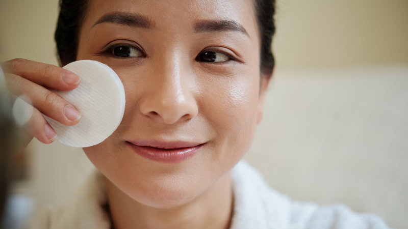 Woman wiping her face with a cotton pad